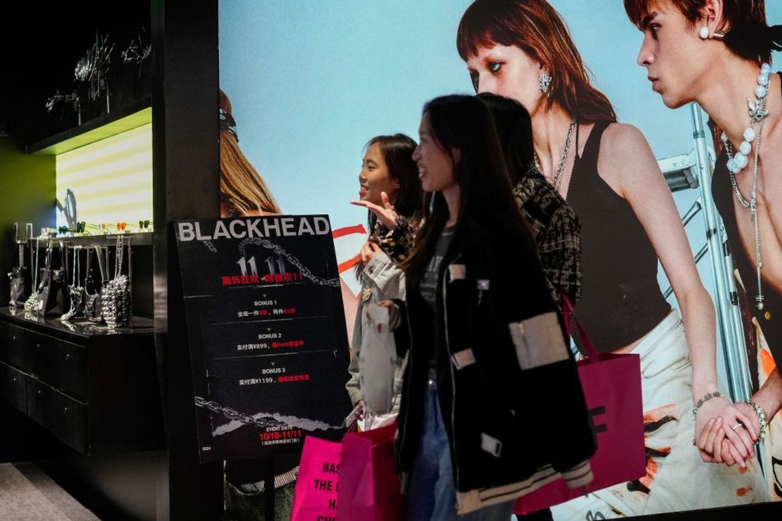 Varias mujeres caminan ante una tienda de accesorios de moda que muestra un cartel para promocionar los descuentos del Día de los Solteros en un centro comercial de Beijing, China, el 11 de noviembre de 2024. Crédito: Andy Wong/AP