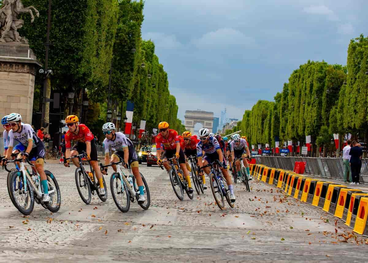 Et hold cykelryttere drejer fra Champs-Élysées ud på Concorde-Pladsen. I baggrunden ses Triumfbuen.