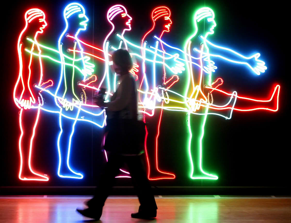 En tilskuer passerer verket Five Marching Men