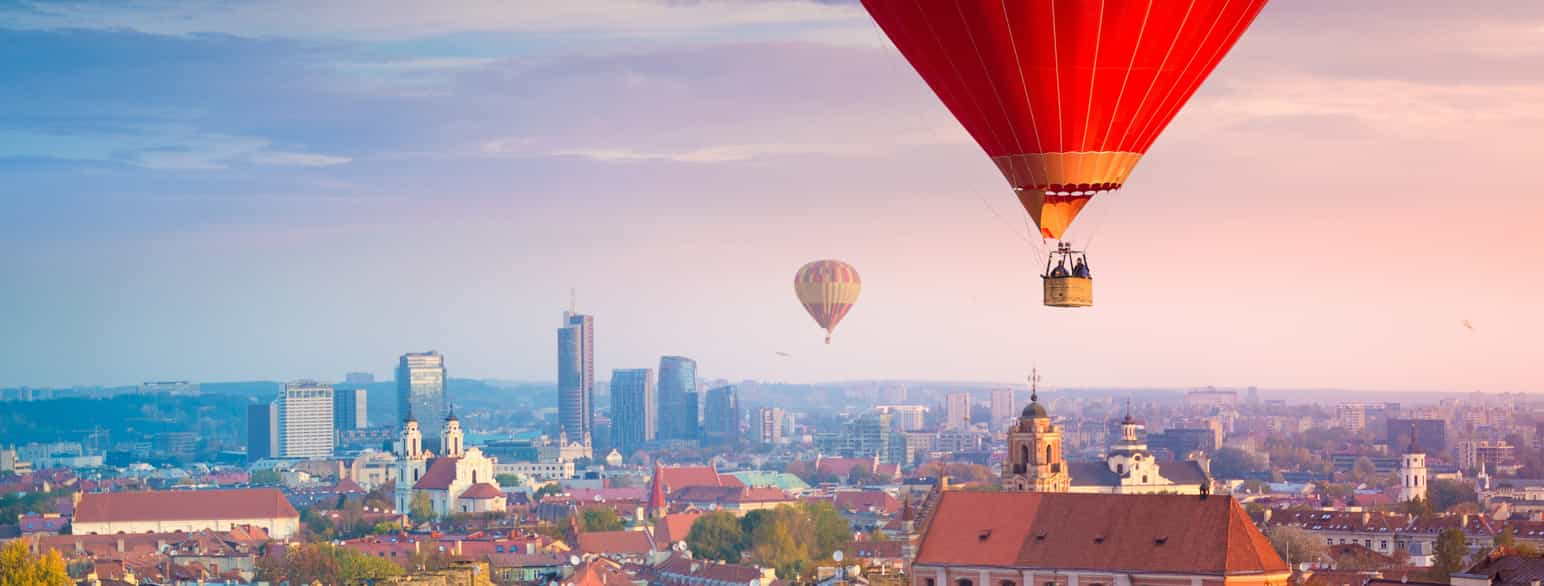 Luftfoto av en by med to røde luftballonger i luften over. Foto