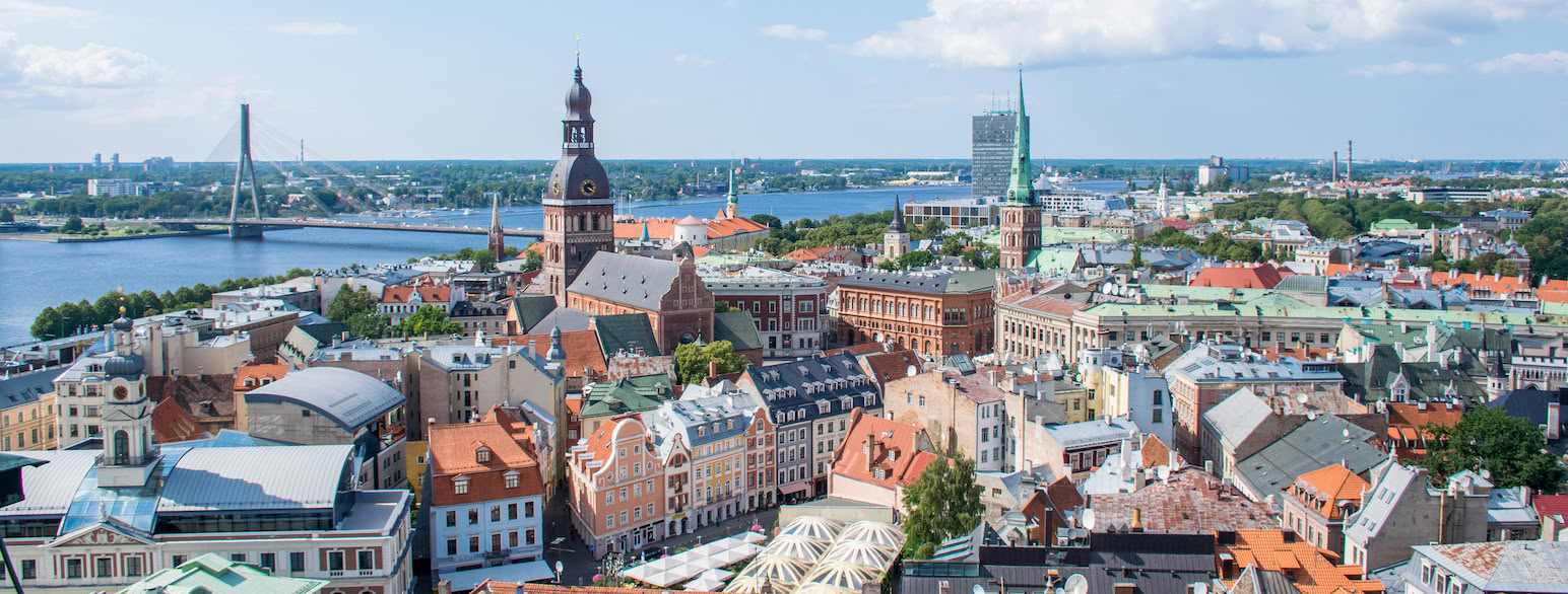 Utsikt over by med en elv i bakgrunnen. En lang bro går over elven og byen fortsetter på den andre siden. Foto