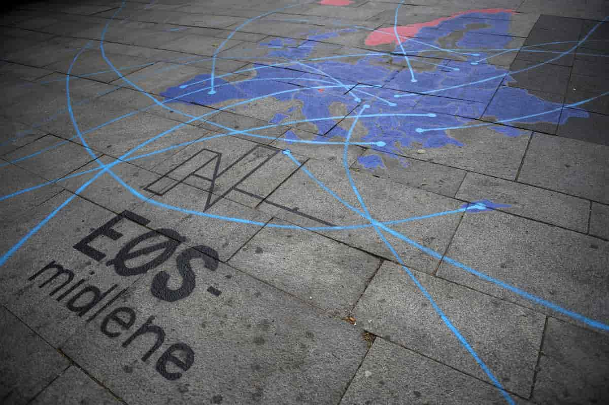 En utendørs plass med steinheller. På hellene er det malt et Europa-kart med Norge og Island i rødt og resten av landene i blått. Over kartet er det malt linjer i lyseblått. Nedenfor kartet står det «EØS-midlene». Foto