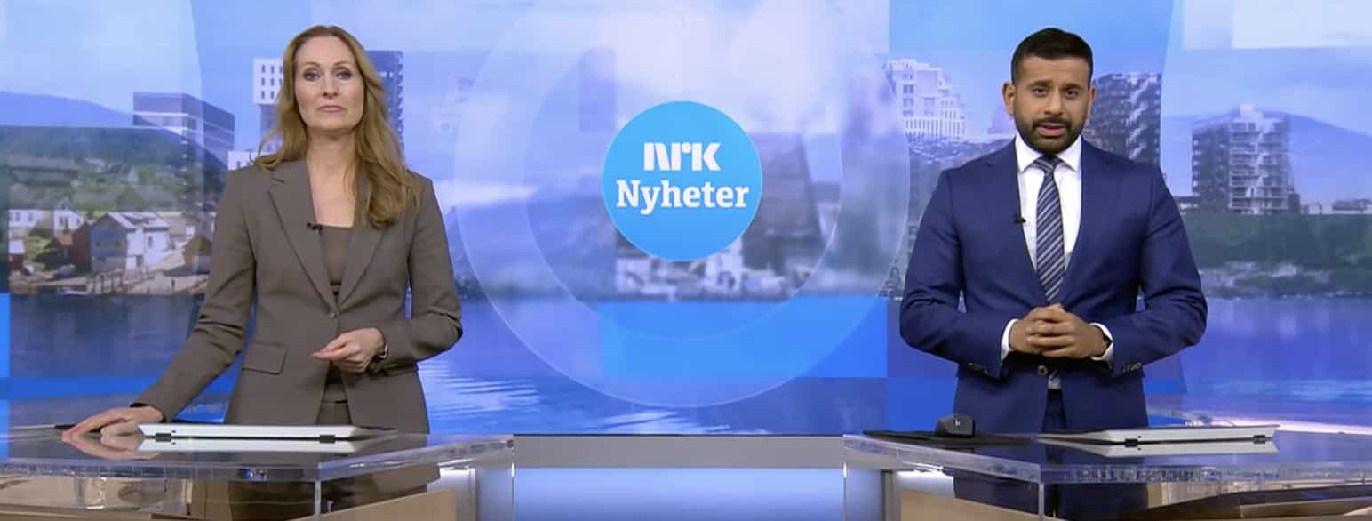 Bildet viser to programledere i et studio. I midten er det et bilde av logoen til NRK nyheter