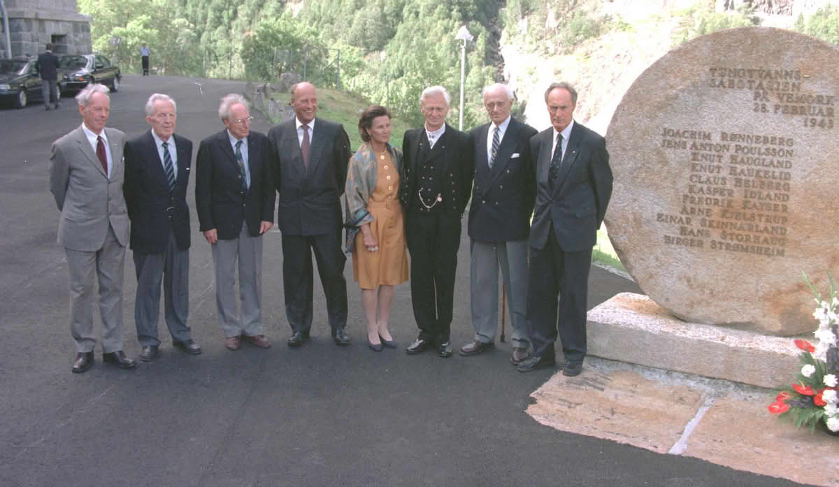 Foto av mennesker so står på rekke ved siden av et rundt monument i stein