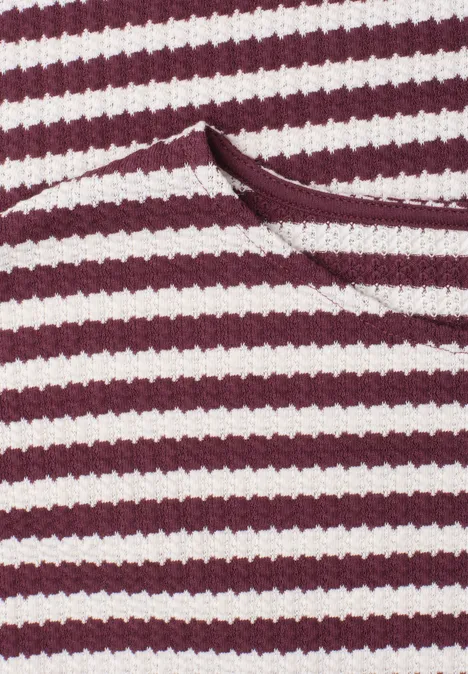 Gebreide jurk rustic rouge Close-up van bordeaux- en witgestreepte stof met een schuine opening of zak.