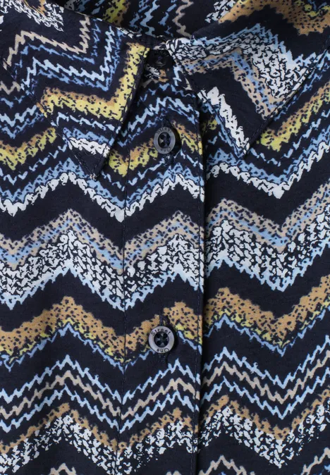 Midi-jurk met zigzagpatroon frozen wave Close-up van een gebreide cardigan met zigzagpatroon in blauw, wit, geel en zwart en knopen.