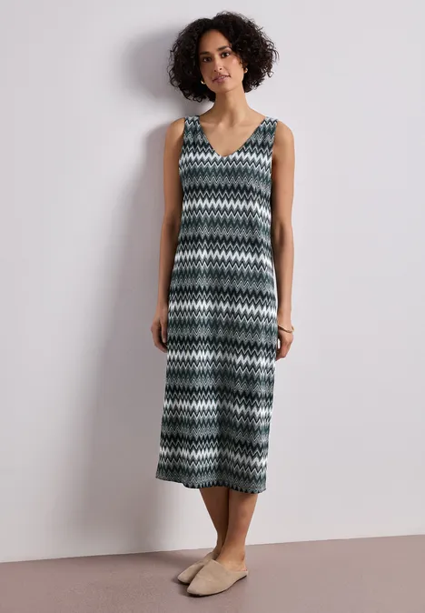 Midi-jurk met V-hals in jacquardstof deep bound green Een persoon draagt een mouwloze midi-jurk met zigzagpatroon en platte espadrilles.