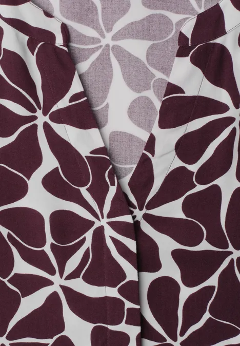 Midi-jurk met gespleten hals en print rustic rouge Close-up van stof met bordeauxrode, abstracte bloembladvormen op een lichte achtergrond.