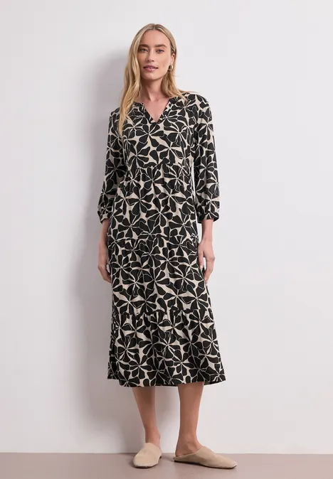 Midi-jurk met gespleten hals in etnische look Black Vrouw in zwarte midijurk met beige sterprint, getailleerd model en beige instappers.