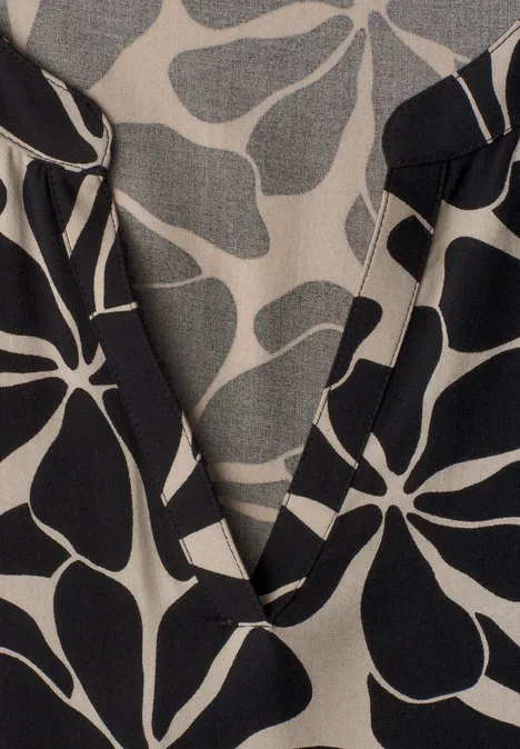 Midi-jurk met gespleten hals in etnische look Black Beige stof met zwart abstract bloemenpatroon en V-hals, close-up.