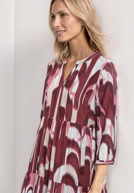 Midi-jurk met gespleten hals in etnische look rustic rouge Vrouw in losvallende rood-witte jurk met abstract patroon en driekwartmouwen.