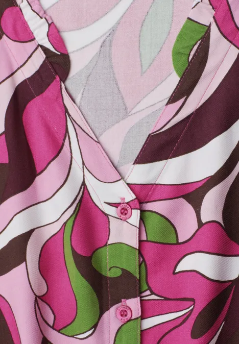 Midi-jurk met V-hals en print magenta dream Close-up van een kleurrijk blousepatroon in roze, wit, bruin en groen met V-hals en roze knopen.