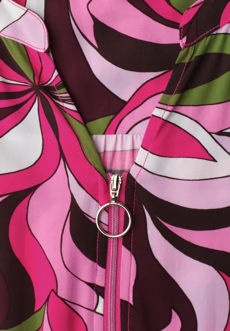 Midi-jurk met gespleten hals en ritssluiting magenta dream Close-up van een ritssluiting op psychedelische stof in roze, zwart, wit en groen.