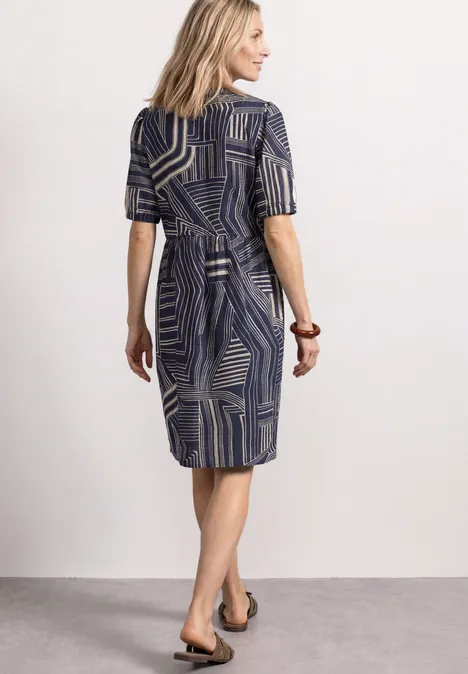 Kniehoge jurk met strikdetail darkest blue Een vrouw in een midijurk met geometrisch patroon en ceintuur, van achteren gezien.