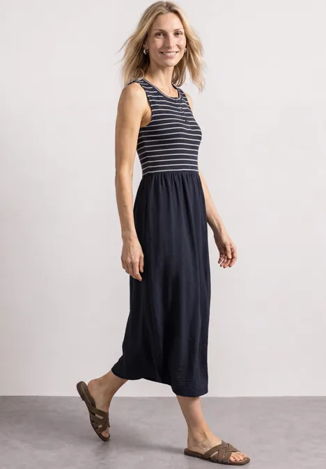 Midi-jurk met verschillende texturen en knoopdetails darkest blue Een lachende vrouw draagt een marineblauw gestreept mouwloos topje met een midirok en sandalen.