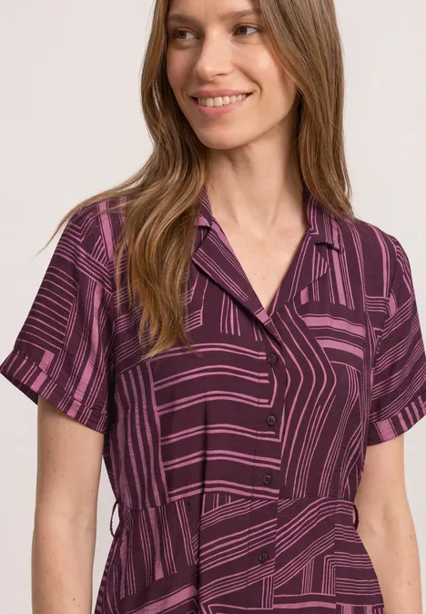 Midi-jurk met bowlingkraag blush berry Een glimlachende vrouw in een kort paars bovenstuk met geometrisch patroon.