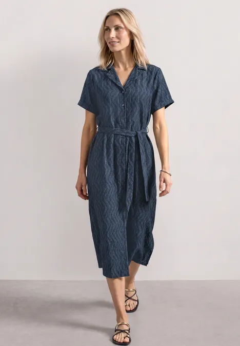 Midi-jurk met bowlingkraag darkest blue Vrouw in getailleerde navyblauwe midi-jurk met korte mouwen, V-hals en ceintuur tegen neutrale achtergrond