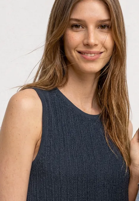 Midijurk van kant met ronde hals darkest blue Vrouw met mouwloos, donker gebreid topje tegen een lichte achtergrond.