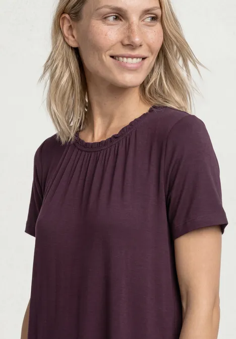 Knielange jersey jurk met ronde hals rustic rouge Vrouw met halflang blond haar draagt een losse paarse t-shirt tegen een lichte achtergrond