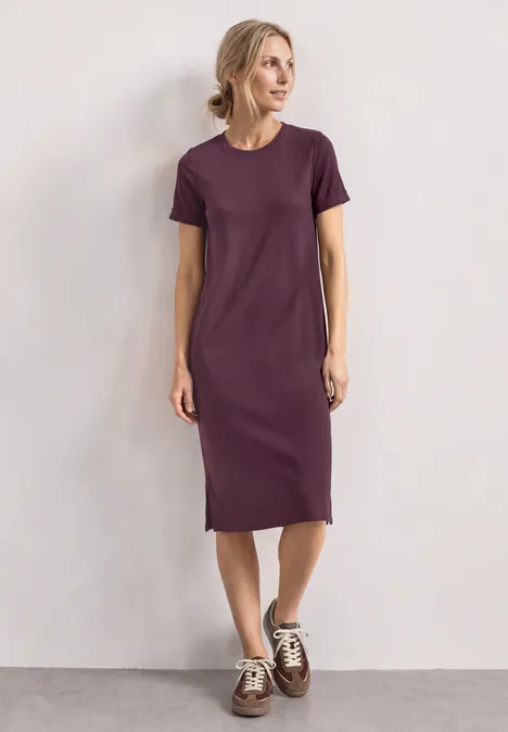 Midijurk met ribbelstructuur en ronde hals rustic rouge Vrouw in eenvoudig paarse midi T-shirtjurk met witte sneakers voor een neutrale achtergrond.