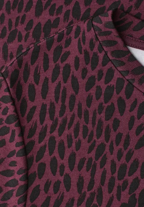 Midi-jurk met grafisch patroon rustic rouge Close-up van een bordeauxrode stof met onregelmatig zwart vlekkenpatroon.