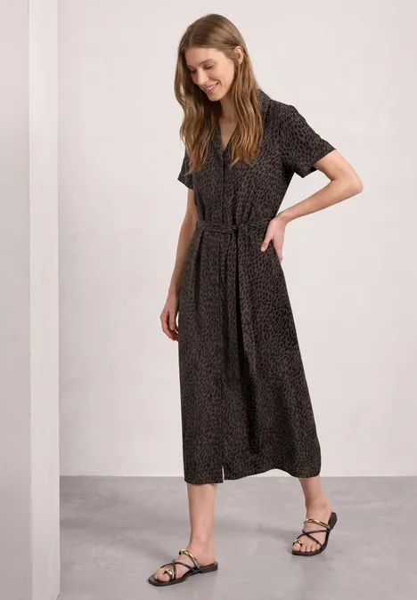 Midi-jurk met bowlingkraag en print molten earth Vrouw draagt zwarte midi-jurk met korte mouwen en dessin, gecombineerd met zwarte platte sandalen.