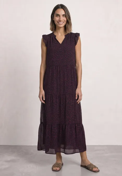 Maxi-chiffonjurk met volants en print rustic rouge Vrouw in een lange, mouwloze, gelaagde jurk met ruches en bloemenpatroon, draagt sandalen.