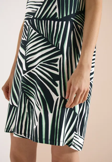 Knielange jersey jurk palm breeze green Close-up van een jurk met groen palmbladpatroon op een witte achtergrond.