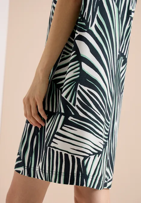 Knielange jurk met ronde V-hals universal blue Een vrouw in zijaanzicht draagt een korte jurk met groen-witte zebraprint.