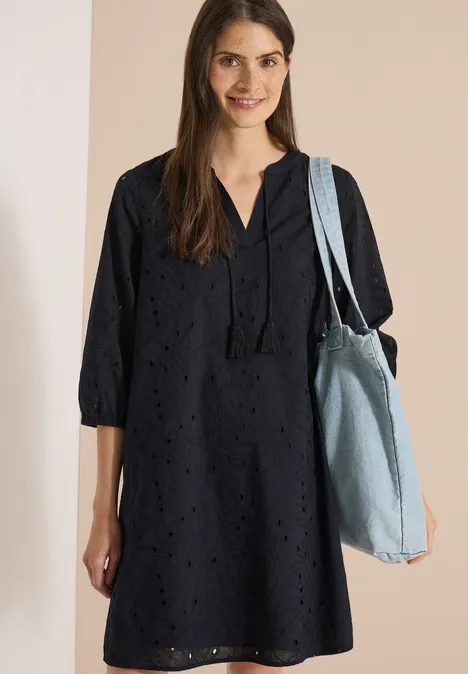 Knielange jurk met 3/4-mouwen en borduursel Black Vrouw in zwarte opengewerkte jurk met 3/4-mouwen en lichte jeans schoudertas.