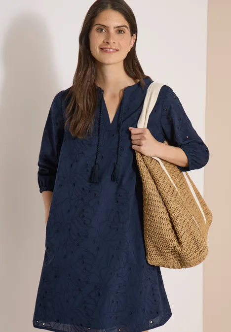 Knielange jurk met 3/4-mouwen en borduursel universal blue Vrouw in een donkerblauwe jurk met borduursels, driekwartmouwen en een rieten tas.