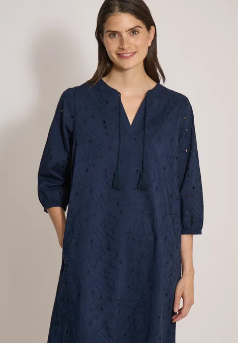 Knielange jurk met 3/4-mouwen en borduursel universal blue Een vrouw draagt een marineblauwe, geborduurde jurk met V-hals, kwastjes, driekwartmouwen en zakken.