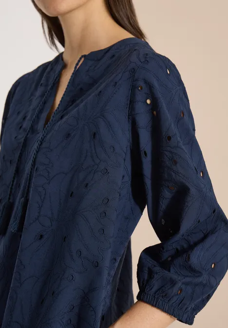 Knielange jurk met 3/4-mouwen en borduursel universal blue Donkerblauw geborduurd damestop met ajourdetails en lange mouwen tegen een lichte achtergrond.