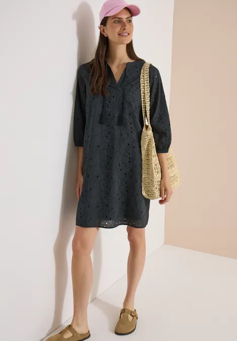 Knielange jurk met 3/4-mouwen en borduursel palm breeze green Vrouw in marineblauwe, lange mouwen jurk met opengewerkt patroon, strooien tas en pet.