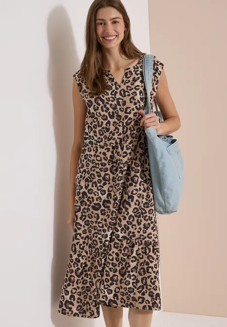 Midi-jurk met split in de hals en luipaardprint urban taupe Een vrouw in een lange luipaardjurk met een lichtblauwe tas, staand voor een neutrale muur.
