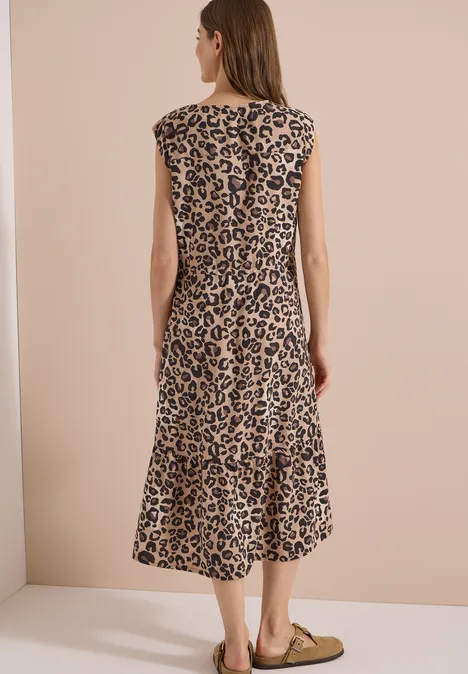 Midi-jurk met split in de hals en luipaardprint urban taupe Vrouw van achteren in mouwloze midi-jurk met luipaardprint en platte ballerina’s tegen een beige achtergrond.