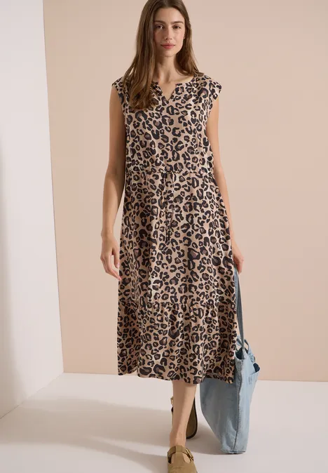 Midi-jurk met split in de hals en luipaardprint urban taupe Vrouw in midi-jurk met luipaardprint en blauwe tas tegen een beige achtergrond.