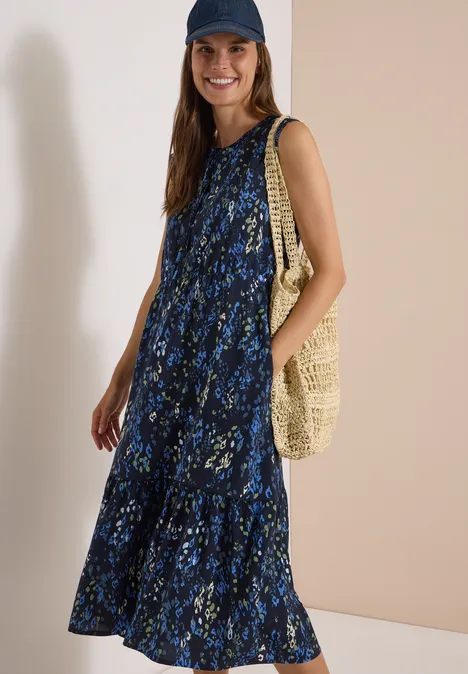 Midi-jurk met split in de hals en print urban dark blue Vrouw lacht in een blauw bloemen maxi-jurk, met pet en strozak