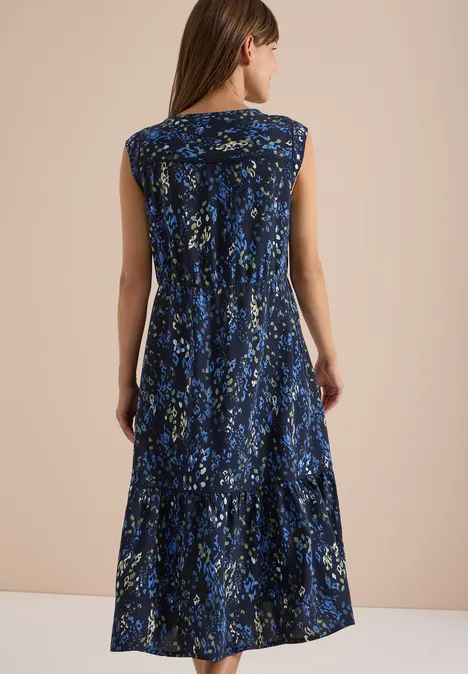 Midi-jurk met split in de hals en print urban dark blue Vrouw van achteren in een blauwe, mouwloze midijurk met abstract bloemenpatroon.