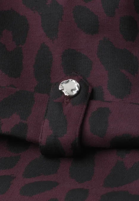Midijurk met ronde hals en luipaardprint very berry Close-up van een bordeauxrode stof met zwarte luipaardvlekken en een zilveren knoop.