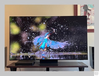 A large screen tv with the screen showing a bird emerging out of water in slow motion