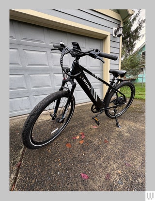 Side view of Lectric Xpress 750 a black electric bike in front of a home garage