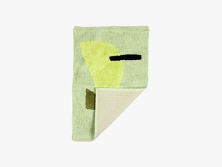 Cold Picnic Bath Mat a green mat with abstract shapes for decoration and the corner curled up