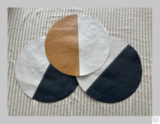 Uashmama Tec Placemats 3 circular mats with two being half black and half white and the mat on top being half brown and...