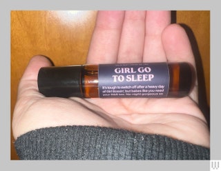 A palm holding Candier essential oil small dark tube with blue and pink label saying Girl Go To Sleep