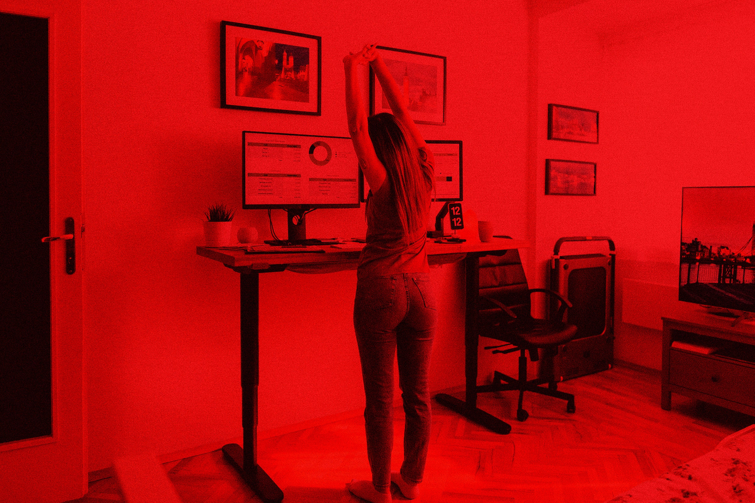 A woman stretching at a standing desk with computers