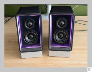 Edifier QR65 black rectangular speakers with purple interior trim sitting on a wooden desk