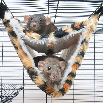 Two small animals resting in a soft, fleece-lined hammock suspended inside a wire cage, demonstrating use of the hanging bed accessory.
