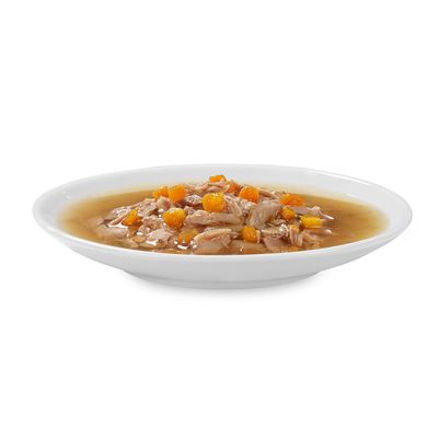 Comida húmeda para mascotas servida en plato blanco, con trozos de carne y pequeños cubos naranjas en salsa.