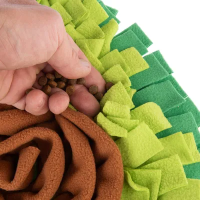 Kéz barna kroketteket helyez zöld és barna filc szimatolószőnyegbe, alkalmas interaktív játékra és etetésre. Kéz barna kroketteket helyez zöld és barna filc szimatolószőnyegbe, alkalmas interaktív játékra és etetésre.